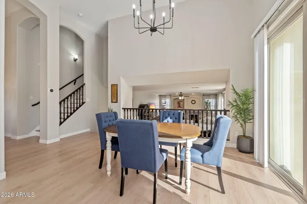 a dining room with wooden floor a chandelier a wooden table and chairs
