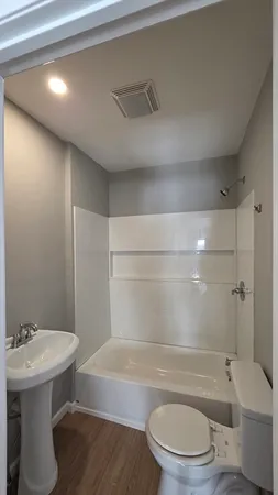 a bathroom with a bathtub shower sink mirror vanity and toilet