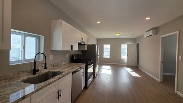 a kitchen with granite countertop a sink appliances cabinets and wooden floor