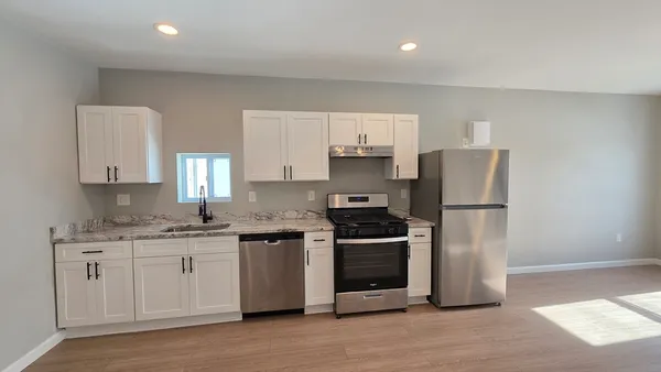 a kitchen with stainless steel appliances granite countertop a stove a refrigerator a sink a microwave and white cabinets