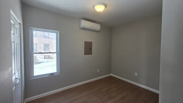 an empty room with a window and wooden floor