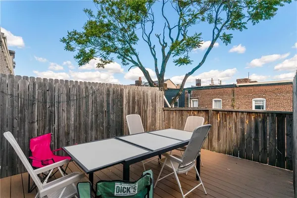 a view of a patio with table and chairs with wooden floor and fence