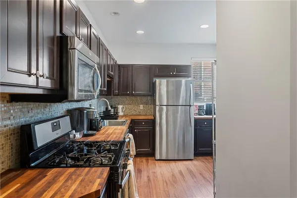 a kitchen with stainless steel appliances granite countertop a refrigerator a stove and a sink with wooden floor