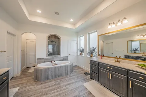 a spacious bathroom with a double vanity sink a mirror and a bathtub