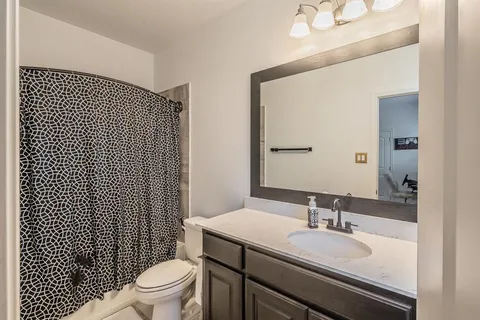 a bathroom with a granite countertop toilet a sink and a mirror