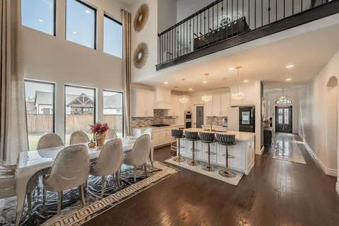 a dining room with furniture a floor to ceiling window and kitchen view