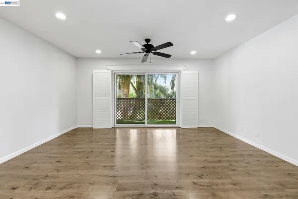 an empty room with wooden floor and a ceiling fan