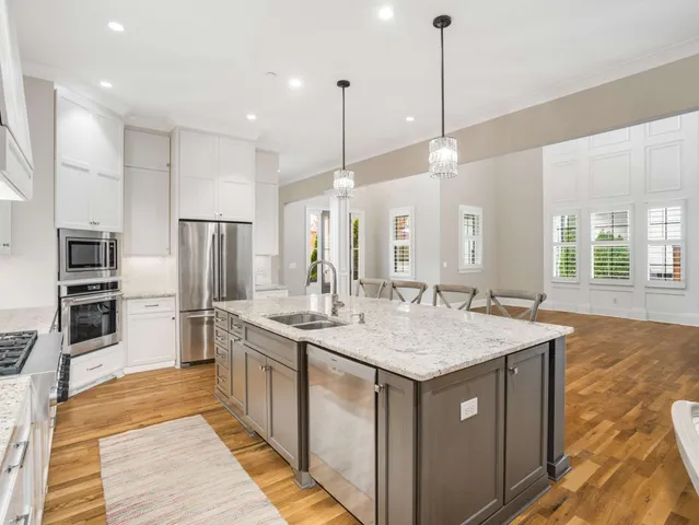 a kitchen with stainless steel appliances granite countertop a dining table chairs stove and white cabinets