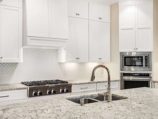 a view of a sink and dishwasher with white cabinets