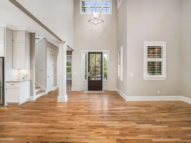 a view of an empty room with window and wooden floor