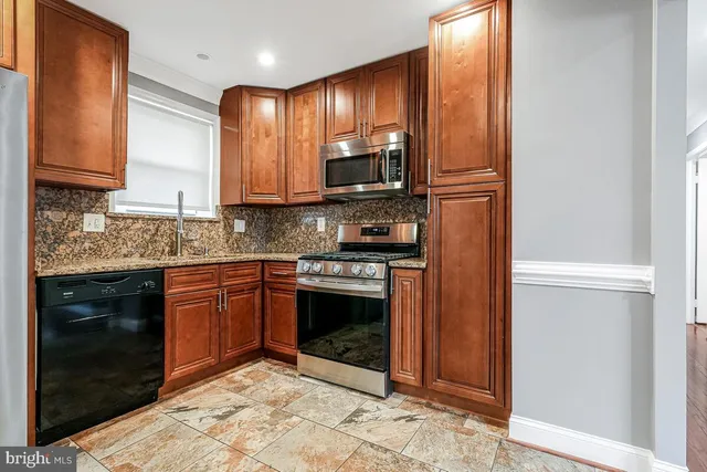 a kitchen with stainless steel appliances granite countertop wooden cabinets a stove top oven a sink and dishwasher