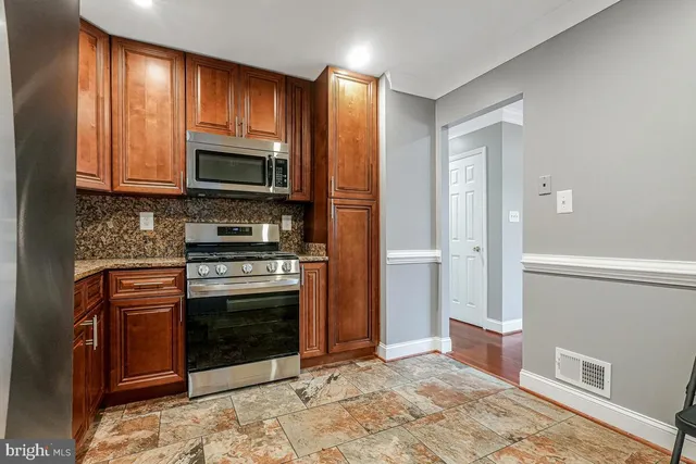 a kitchen with granite countertop wooden cabinets stainless steel appliances and a window