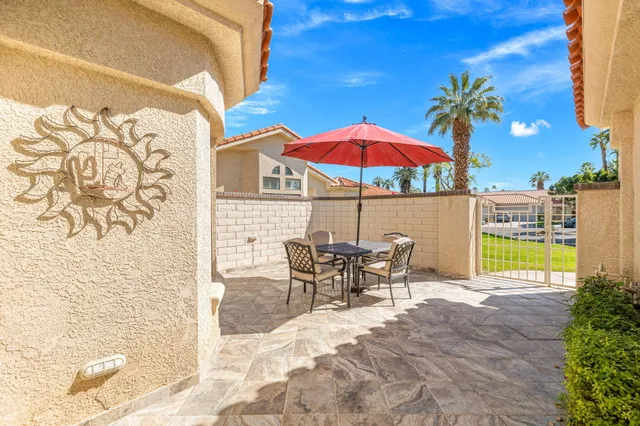 a view of a patio with a table and chairs under an umbrella