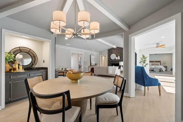 a dining room with wooden floor a chandelier a wooden table and chairs