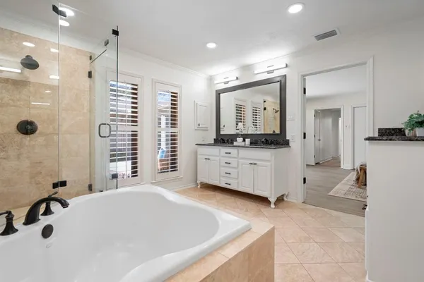 a bathroom with a tub a double vanity sink and mirror