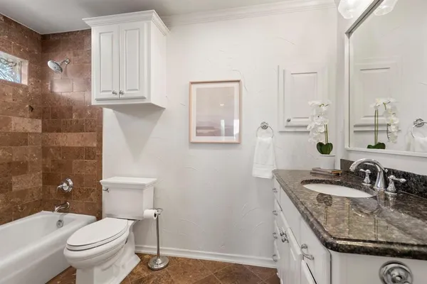 a bathroom with a granite countertop double vanity sink a mirror and a toilet