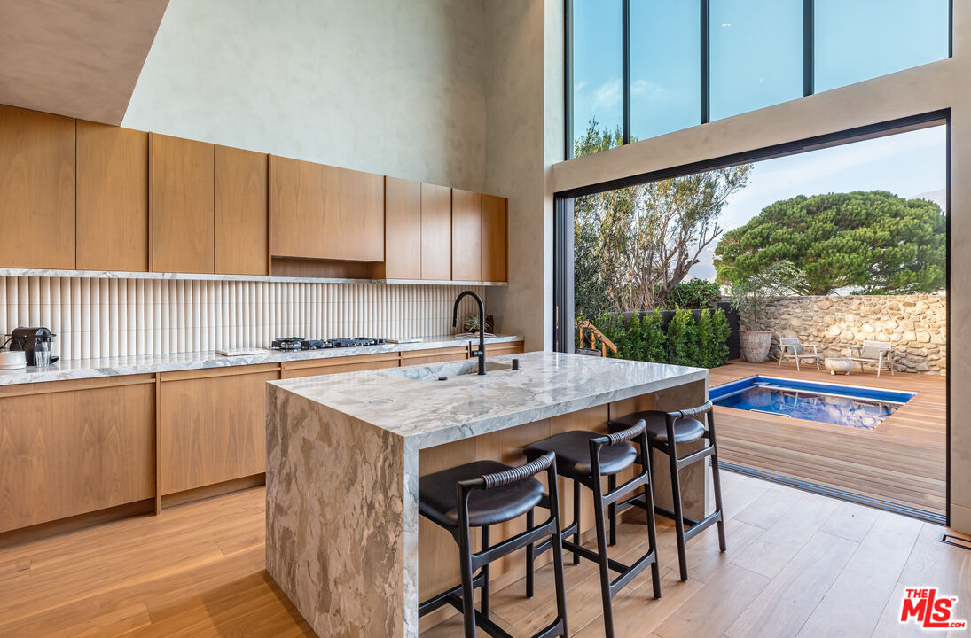 23505 Malibu Colony Road Malibu, CA 90265 - Photo 13 of 39 a kitchen with a table chairs sink and cabinets