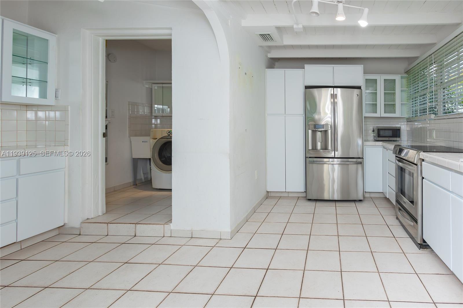 6765 Southwest 51st Street Miami, FL 33155 - Photo 30 of 43 a kitchen with a refrigerator a oven and white cabinets