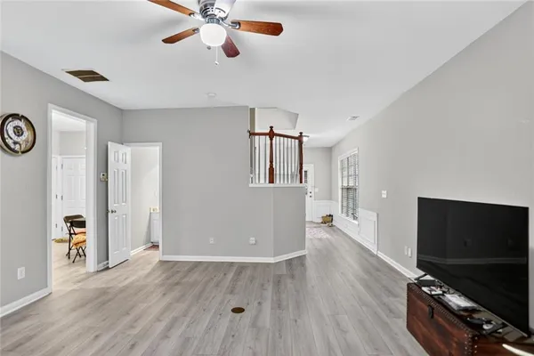 a view of a livingroom with a flat screen tv wooden floor and a ceiling fan