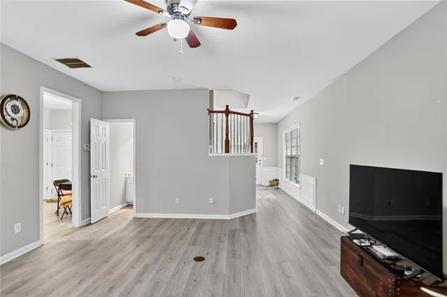 a view of a livingroom with a flat screen tv wooden floor and a ceiling fan