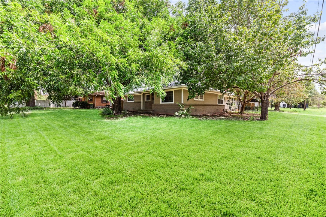 a view of a house with a big yard and large trees