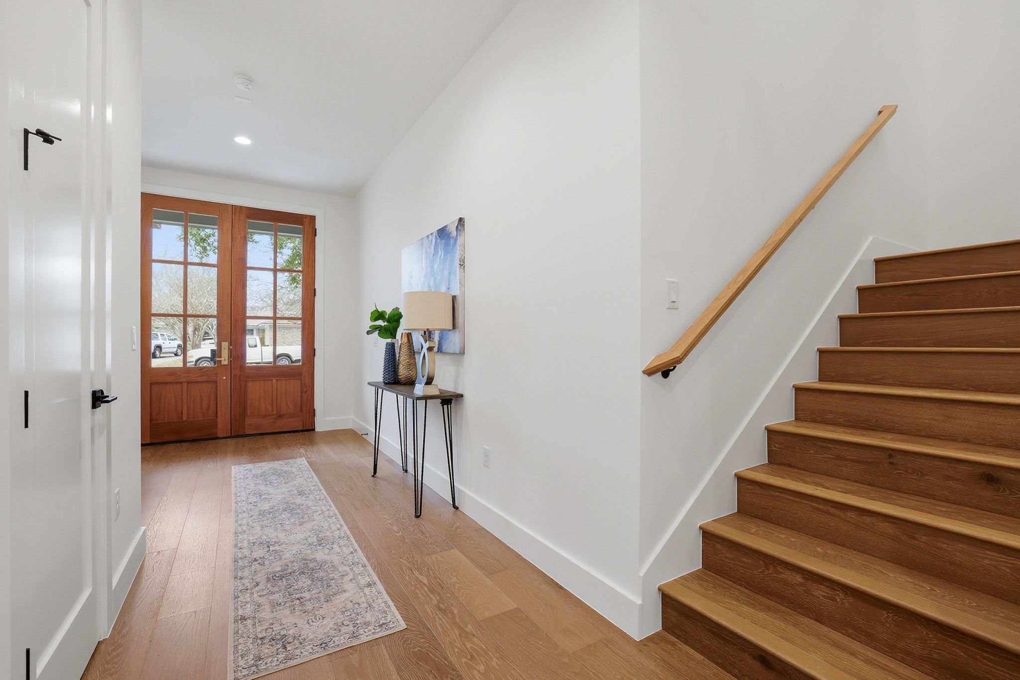 6611 Lexington Road Austin, TX 78757 - Photo 7 of 37 Entryway featuring double French doors with transom windows, wood-finish flooring, a modern wood handrail, and crisp white walls