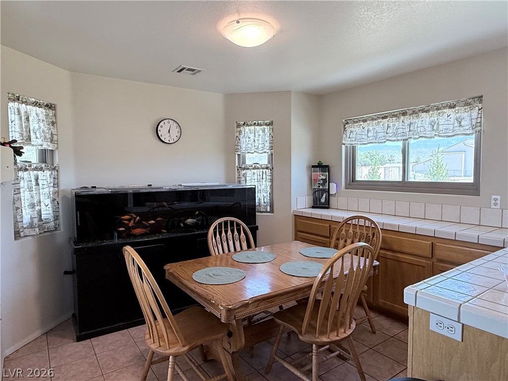 1220 East Gamebird Road Pahrump, NV 89048 - Photo 7 of 49 A charming dining space with warm cabinetry and abundant natural light from multiple windows.