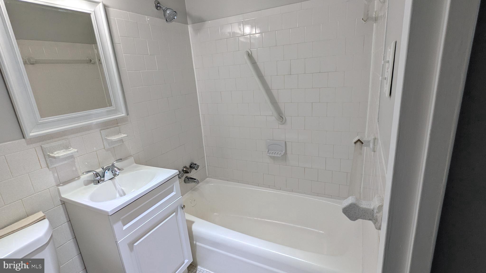 4600 Duke Street, Unit 620 Alexandria, VA 22304 - Photo 29 of 40 a white bath tub sitting next to a white sink and a mirror