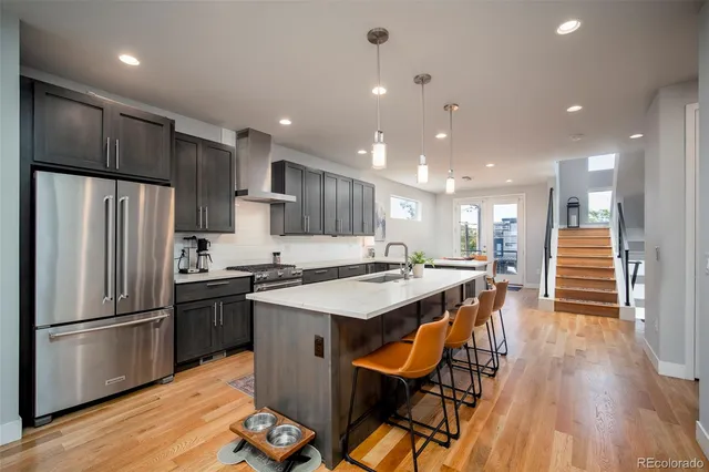a kitchen with stainless steel appliances granite countertop a table chairs wooden floors and white cabinets