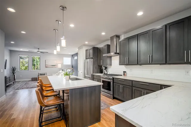 a kitchen with stainless steel appliances kitchen island granite countertop a sink a stove a dining table and chairs