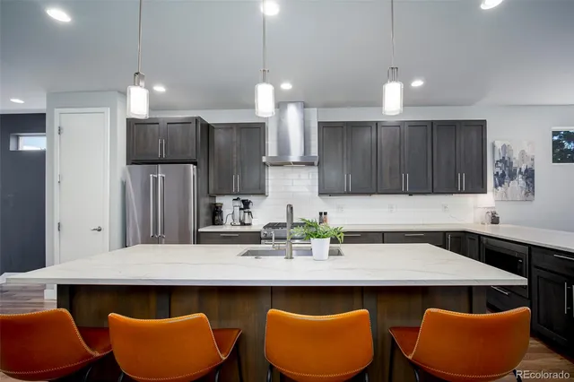 a kitchen with stainless steel appliances granite countertop a table chairs in it and wooden floors