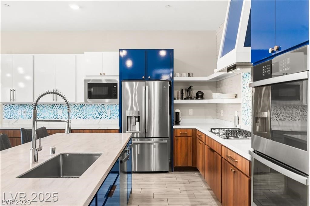 103 Reflection Cove Drive Henderson, NV 89011 - Photo 22 of 66 Kitchen with stainless steel appliances, open shelves, tasteful backsplash, exhaust hood, and wood finish floors