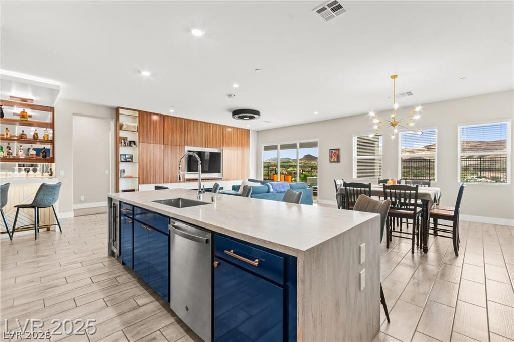 103 Reflection Cove Drive Henderson, NV 89011 - Photo 23 of 66 Kitchen featuring blue cabinets, a kitchen island with sink, wood finish floors, light stone countertops, and recessed lighting