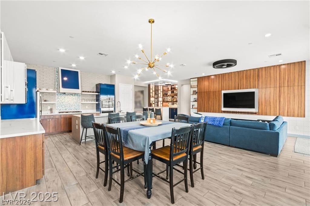 103 Reflection Cove Drive Henderson, NV 89011 - Photo 25 of 66 Dining room featuring a chandelier, light wood-type flooring, wood walls, and recessed lighting
