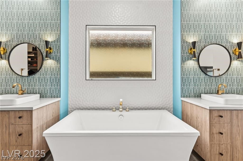 103 Reflection Cove Drive Henderson, NV 89011 - Photo 32 of 66 Bathroom with two vanities, a freestanding tub, and tile walls