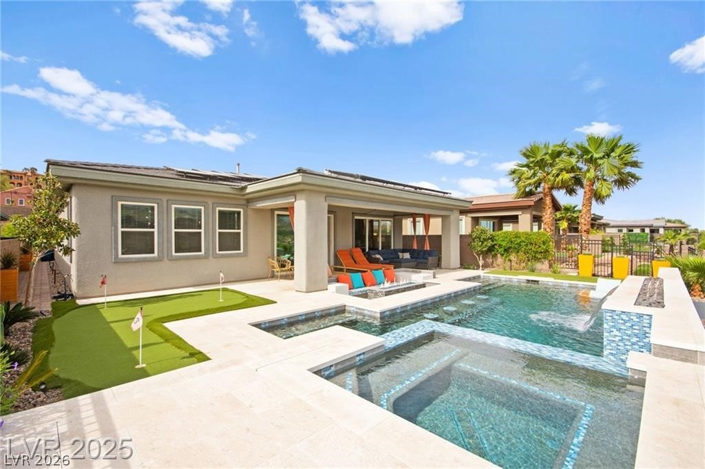 103 Reflection Cove Drive Henderson, NV 89011 - Photo 62 of 66 Back of property with a patio, a fenced backyard, a putting green, stucco siding, and solar panels