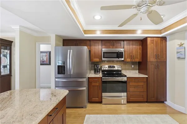 a kitchen with stainless steel appliances granite countertop a refrigerator a stove and a sink with wooden floor