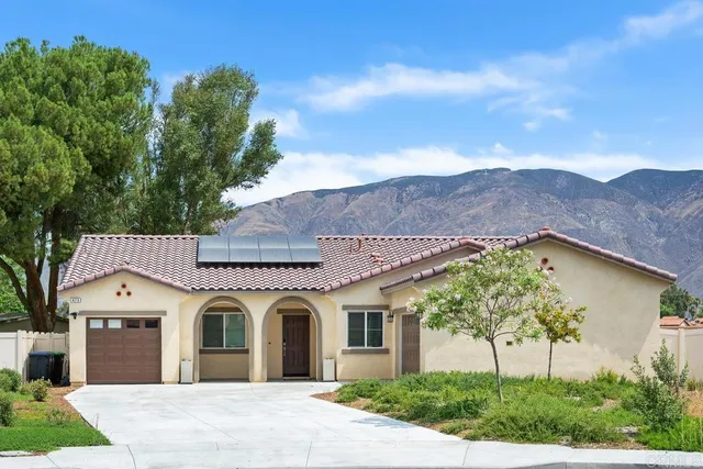 a view of a white house with a big yard and potted plants