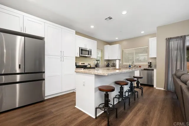 a kitchen with kitchen island a refrigerator a stove a dining table and chairs with wooden floor