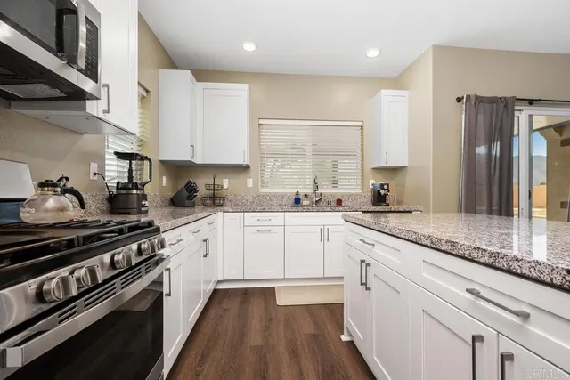 a kitchen with stainless steel appliances white cabinets a sink stove and refrigerator