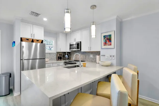 a kitchen with stainless steel appliances a refrigerator a stove a sink and white cabinets with wooden floor