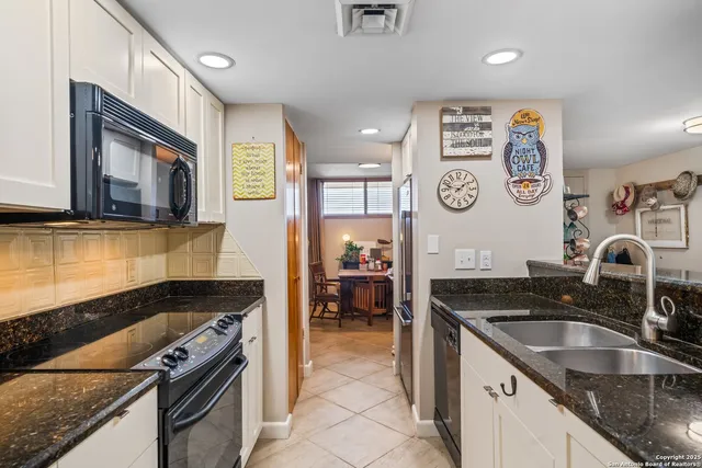 a kitchen with granite countertop stainless steel appliances a stove sink and cabinets