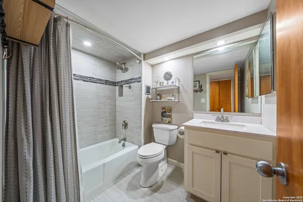 a bathroom with a sink a toilet a mirror a bathtub and shower