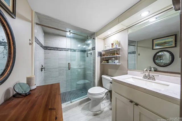 a bathroom with a granite countertop sink toilet a mirror and shower