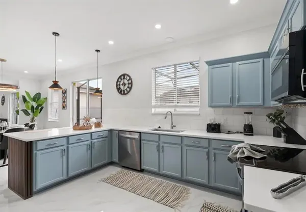 a kitchen with stainless steel appliances a refrigerator a sink a center island and white cabinets