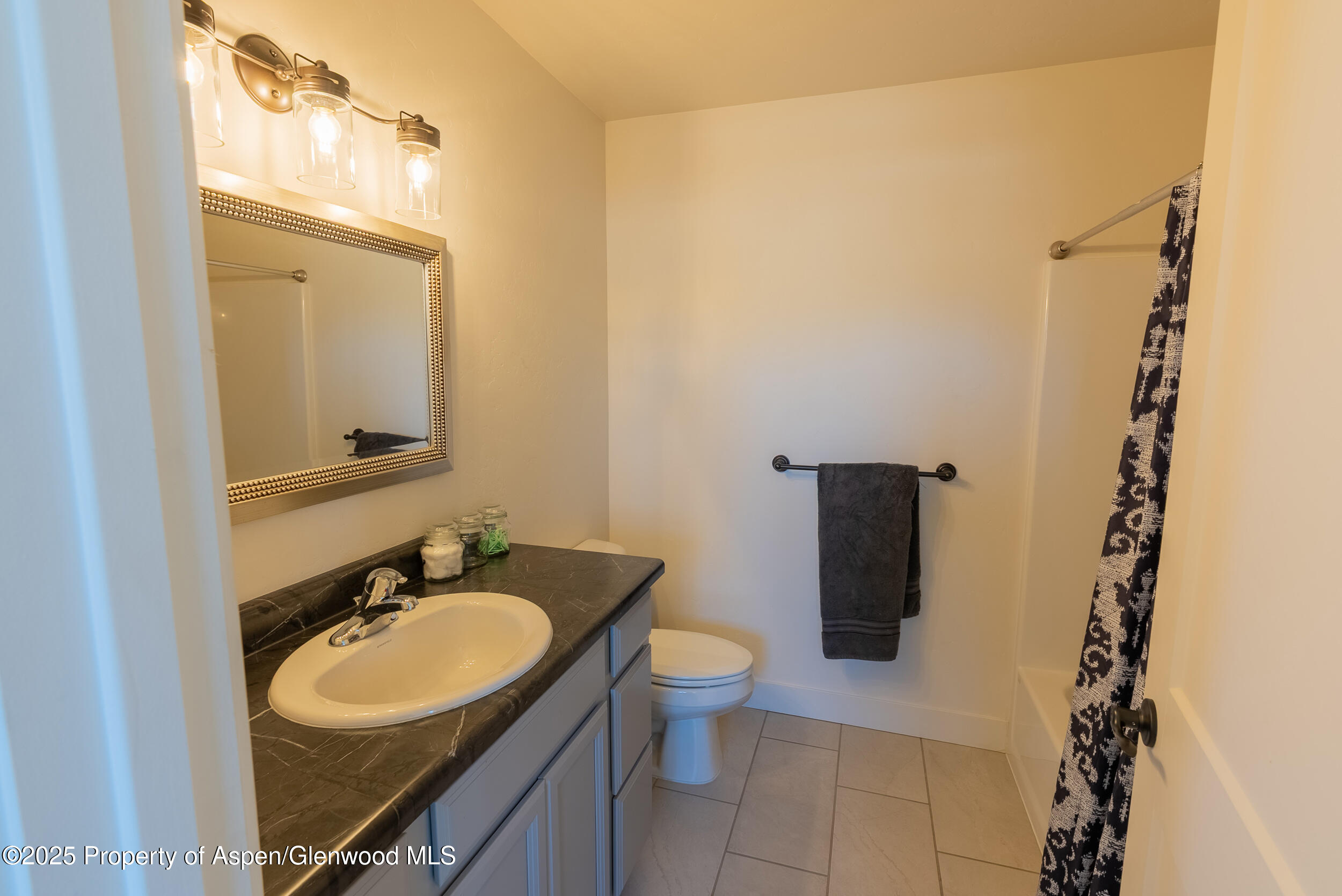 1149 East 17th Street Rifle, CO 81650 - Photo 13 of 16 a bathroom with a granite countertop sink toilet and a mirror