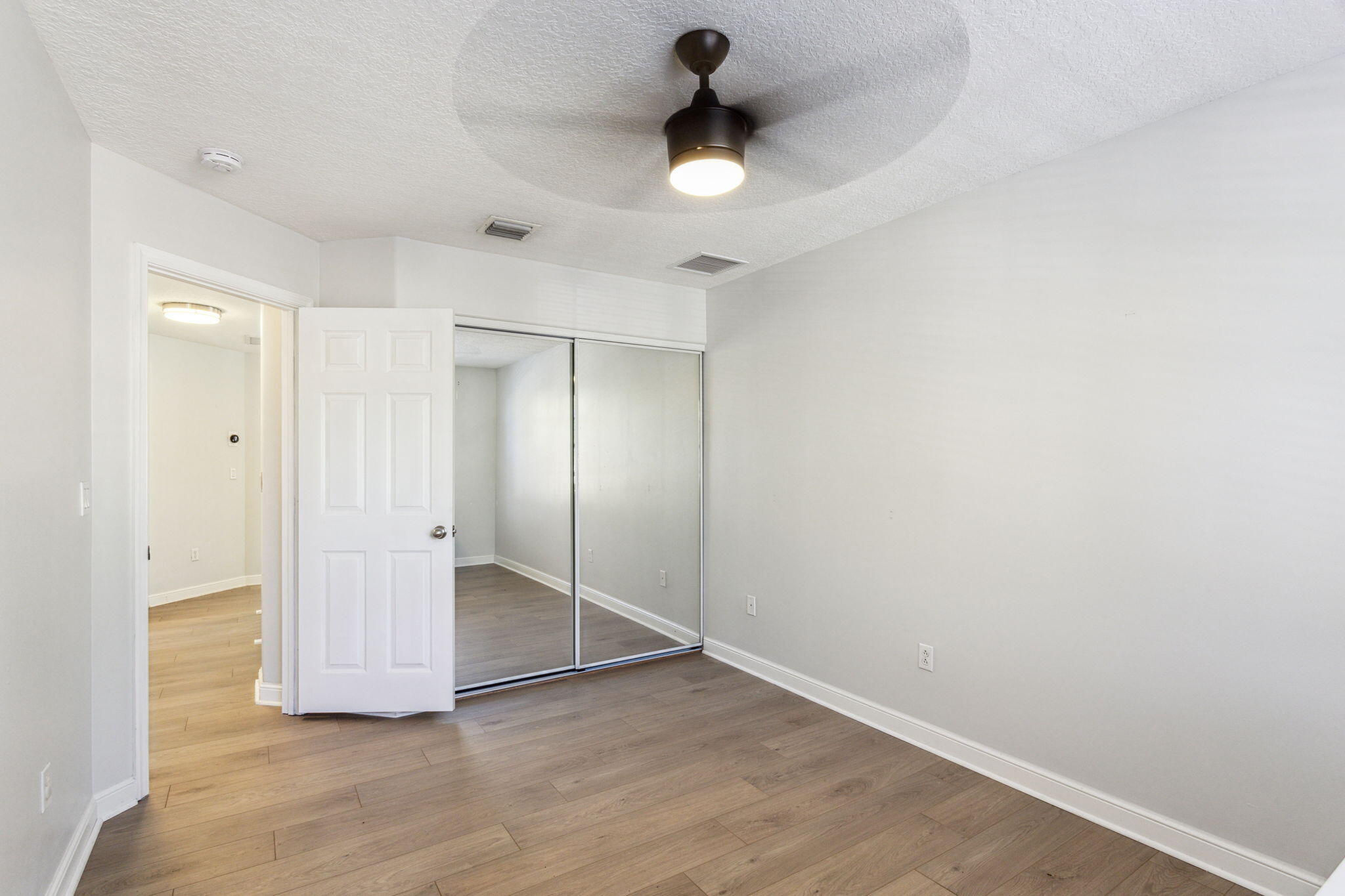 4816 South Classical Boulevard Delray Beach, FL 33445 - Photo 35 of 44 an empty room with wooden floor and fan chandelier