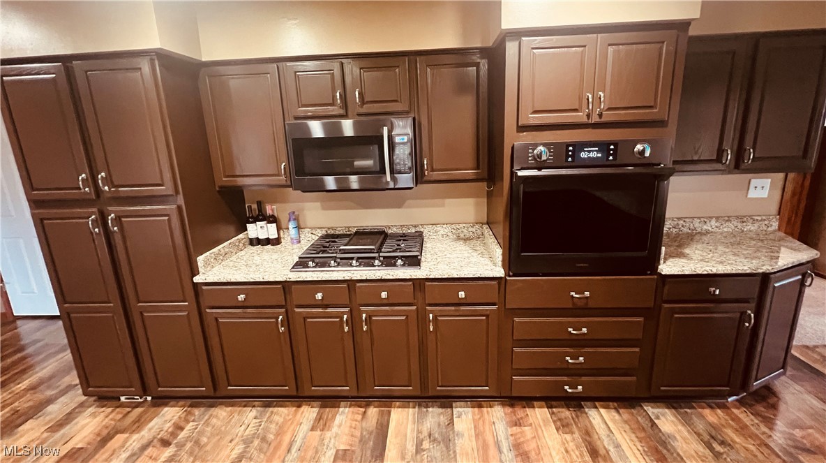 11525 Rapp Road New Middletown, OH 44442 - Photo 13 of 32 Kitchen featuring stainless steel appliances, dark wood-style floors, light stone countertops, and dark brown cabinets
