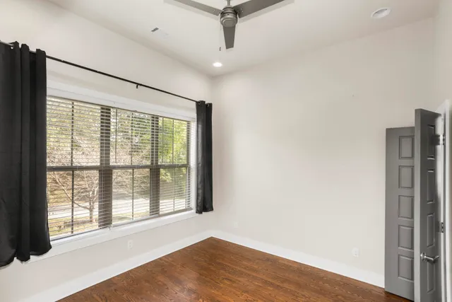 a view of an empty room with a window and wooden floor