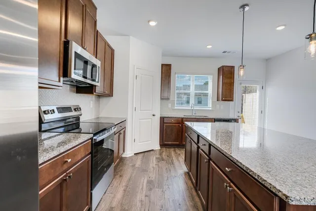 a kitchen with stainless steel appliances granite countertop a stove a sink and a refrigerator